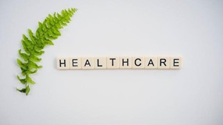 Word Healthcare in Scrabble letters and a leaf.