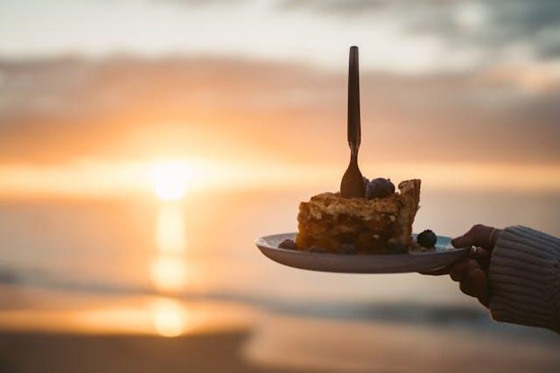 person holding a piece of pie during sunset