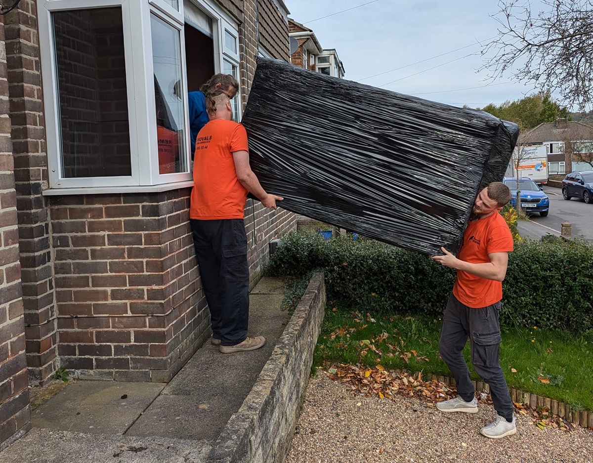 Removal Men Moving a Sofa Through a Window